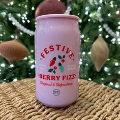 a can of festive berry fizz sitting on a table next to a christmas tree