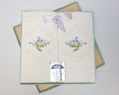 an open book with blue flowers on it and a ribbon tied around the front cover