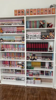 a white book shelf filled with lots of books on top of wooden floored floors