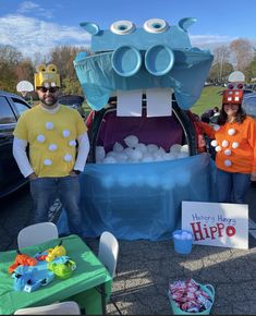 two people in costumes standing next to a car with an ice ball machine on it