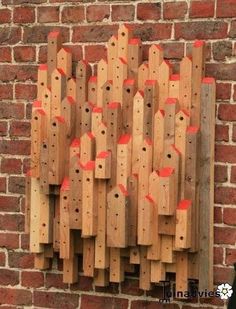 a wall sculpture made out of wooden planks and orange tape on the side of a brick building