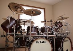 a drum kit sitting in front of a window with the words tama on it