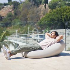 a man is laying on an inflatable chair outside with his feet propped up