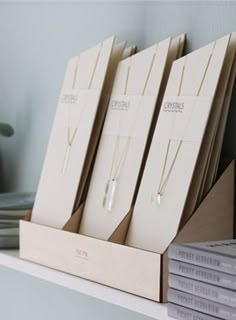 three necklaces are sitting in a wooden holder on a shelf next to some books