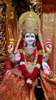 a statue of the hindu god person sitting in front of a gold and red background