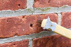 a brick wall with a paint brush sticking out of it's center and the top part of its handle