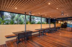 an empty restaurant with tables and chairs on the wooden floor, along with large panoramic windows