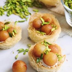 three small baskets filled with food sitting on top of a white counter next to green leaves