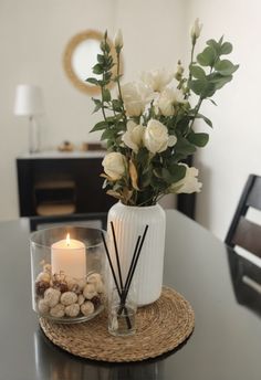 a vase filled with white flowers sitting on top of a table next to a candle