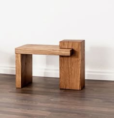 a wooden bench sitting on top of a hard wood floor next to a white wall