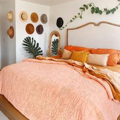 a bed with many hats on the wall above it and a mirror in the corner