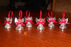 six small silver bells with red bows on them sitting on a wooden table next to each other