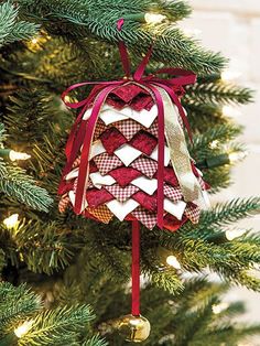 a christmas ornament hanging from the top of a tree with red and white ribbons