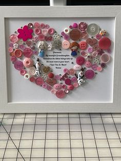 a heart made out of buttons in a frame