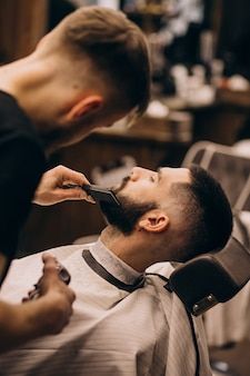 a man getting his hair cut by a barber in a chair at a barbershop