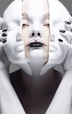 a woman with black and white makeup holding her hands to her face