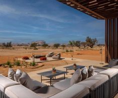 an outdoor seating area with couches and tables in the middle of desert land, under a blue sky