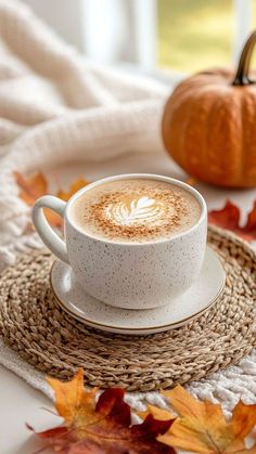 a cup of cappuccino sitting on top of a saucer next to a pumpkin