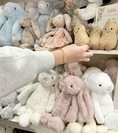 a person is picking up stuffed animals from a shelf