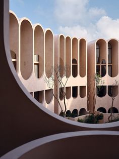 a building with arches and trees in the foreground, seen through a circular window