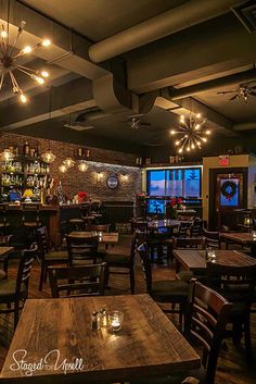 the inside of a restaurant with tables, chairs and bar lights hanging from the ceiling