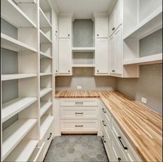 an empty walk in closet with white cabinets and wood counter tops on the shelves,