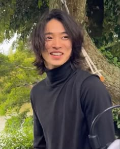 a young man standing next to a tree