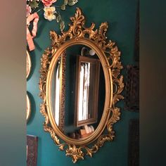 an ornate gold framed mirror hangs on the wall next to a flowery green wall