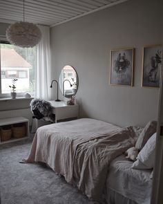 a bed sitting in a bedroom under a window next to a dresser and lamp with pictures on the wall