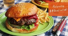 a hamburger and french fries on a green plate with an orange sign in the background