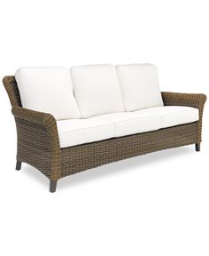 a wicker couch with white pillows on it's back and armrests