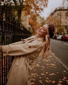 a woman leaning on a fence in the fall