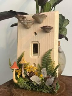 a house made out of wood with plants and rocks around it on a table next to a potted plant