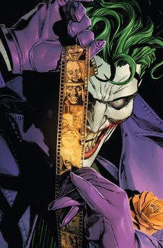 the joker with green hair and purple makeup holding a film strip in front of his face