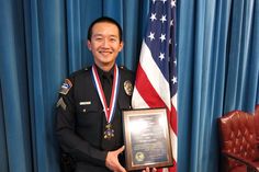 a man in uniform holding an award plaque next to a flag and blue drapes