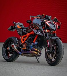 a red and black motorcycle parked in front of a red wall