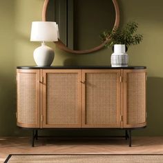 a sideboard with wicker doors and a round mirror