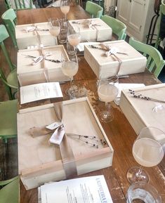 a table with many boxes and glasses on it, all wrapped in white paper bows