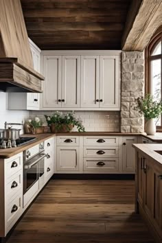 a kitchen with white cabinets and wood floors is pictured in this image, there are potted plants on the counter