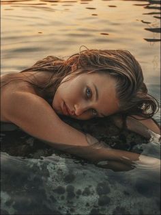 a woman laying on top of a body of water