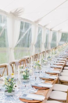 a long table set up with place settings and flowers in vases on the tables