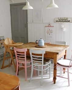 a wooden table and chairs in a room with white walls, wood floors and light fixtures