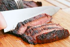 someone is cutting up some meat on a wooden board