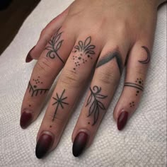 a woman's hand with three different tattoos on her left thumb and one finger