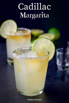 two glasses filled with lemonade and limes next to each other on a table