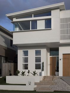 a modern house with white siding and wood doors