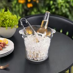 two bottles of wine in a ice bucket on a table with plates and utensils