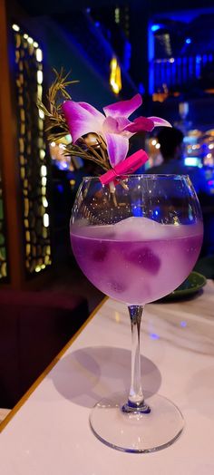 a purple drink in a wine glass on a table