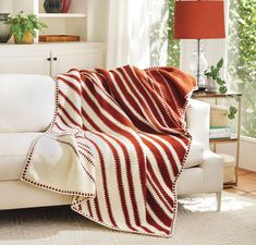 a white couch with a red and white blanket on it