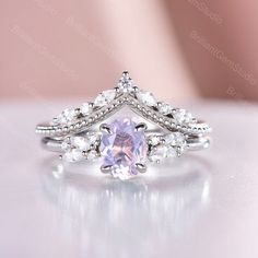 an engagement ring with a pink stone surrounded by white topazte and diamond accents